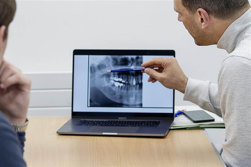 A dental surgeon examining an x-ray of teeth